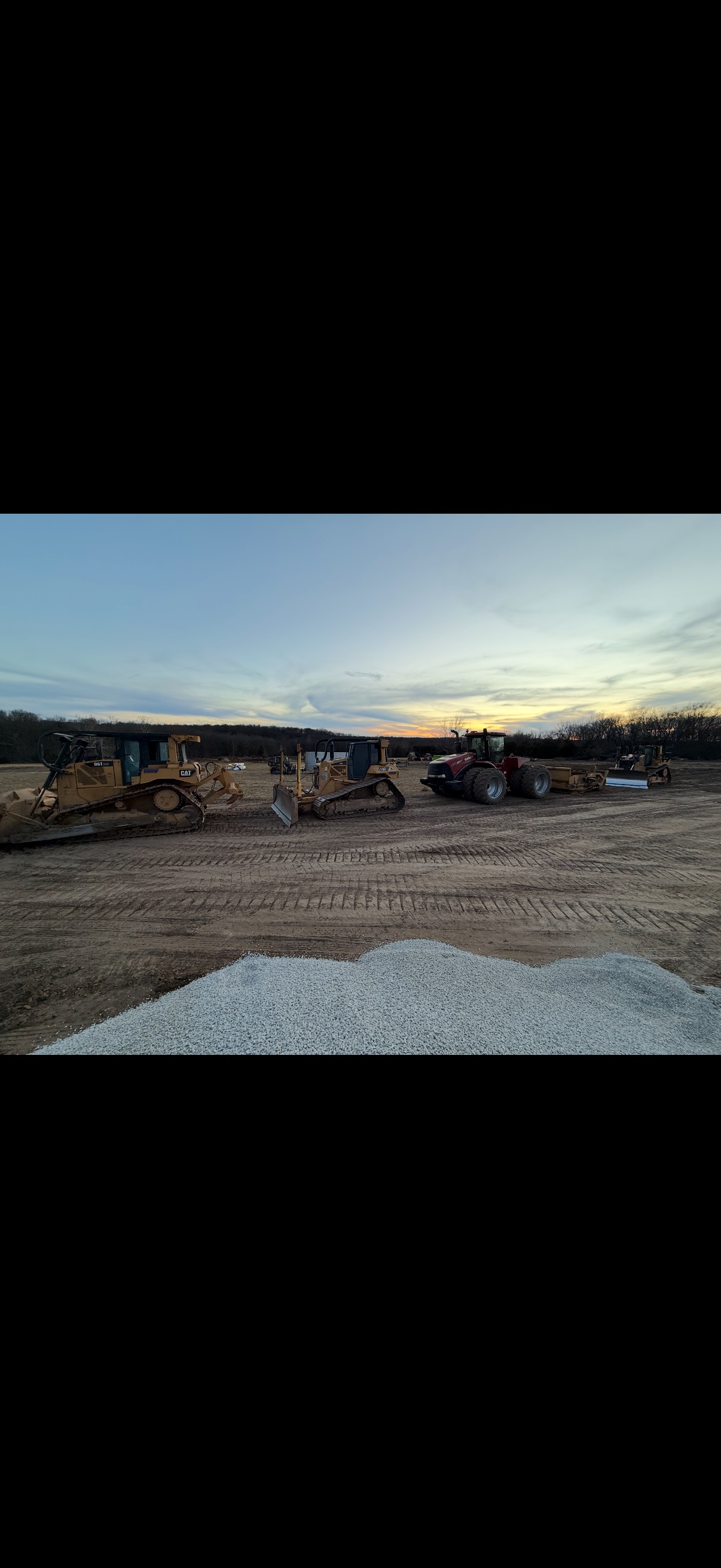 Bulldozers and scraper fleet lined up at sunset on a Windsor, MO job site